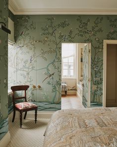 a bedroom with green wallpaper and a chair in front of the bed that is next to it