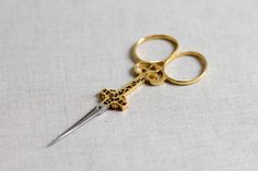 a pair of gold scissors sitting on top of a white table next to each other