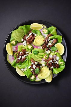 a black plate topped with lettuce and meat