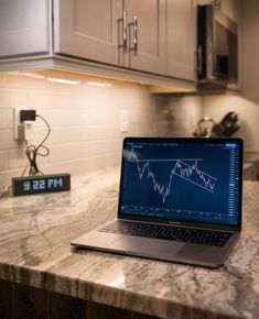 a laptop computer sitting on top of a kitchen counter next to a clock and magnet