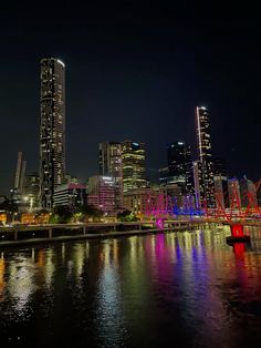 the city is lit up at night with lights reflecting in the water and buildings on both sides