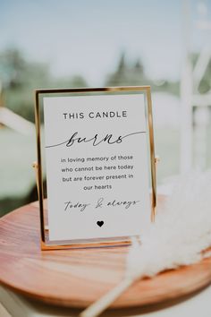 a sign that is on top of a wooden table next to a white bird feather