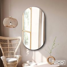 a round mirror hanging on the wall above a wicker chair