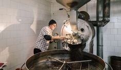 a man standing in front of a machine filled with coffee beans and looking at the ground