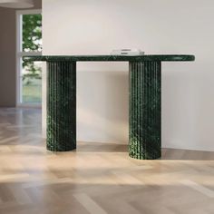 a green marble table sitting on top of a hard wood floor next to a white wall