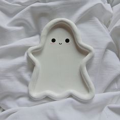 a white plate with a little ghost on it's side, sitting on a bed