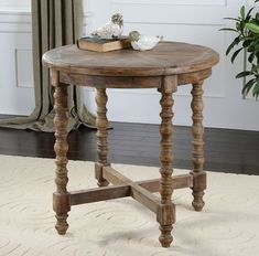 a small wooden table sitting on top of a white floor next to a potted plant