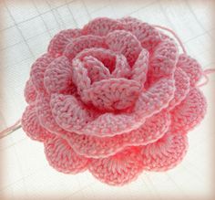 a crocheted pink flower on a white surface