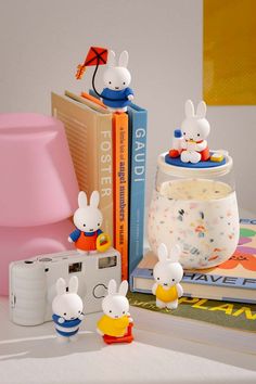 some bunny figurines are sitting on a table next to books and a camera