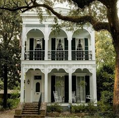 an old white house with black shutters and balconies on the second story