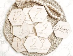 wooden tags with numbers and date on them sitting on a woven place mat next to a bead necklace