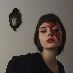 a woman with her face painted red, white and blue is standing in front of a wall