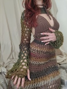 a woman with red hair wearing a crocheted dress and holding her hands on her hips