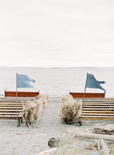 two wooden benches sitting on top of a sandy beach