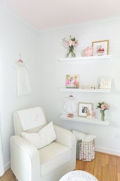 a baby's room with white furniture and flowers on the shelf above it, along with bookshelves