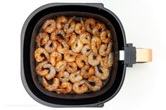 cooked shrimp in an air fryer on a white background