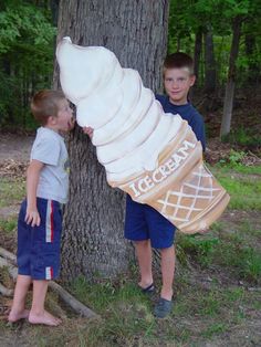 two young boys standing next to a tree with an inflatable bag on it