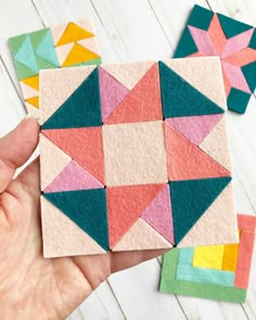 someone is holding up some small pieces of felt that are made to look like geometric shapes