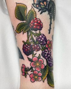 a close up of a person's leg with flowers and leaves on the arm