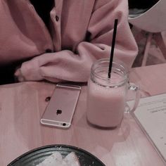 a person sitting at a table with a cell phone in front of them and a drink next to it