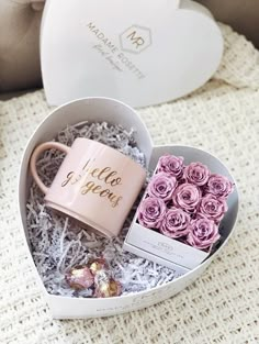 a heart shaped box filled with pink roses and a coffee mug