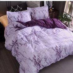 the comforter is made up with purple marbled sheets and pillow cases on it