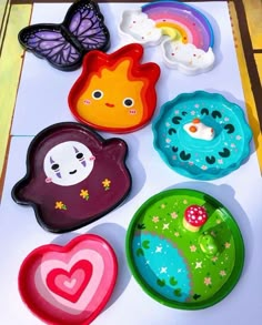 colorful plates with different designs on them sitting on a white table top next to a butterfly