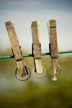 three pairs of wooden clothes pegs hanging from a line with metal rings on them