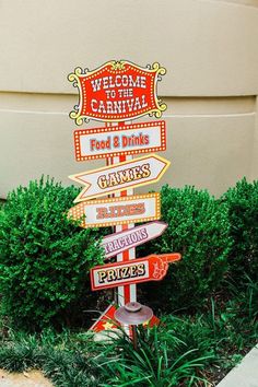 a street sign with many different signs on it in front of a building and bushes