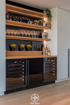 a bar with lots of bottles and glasses on top of the shelves in front of it