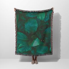 a woman is standing in front of a green leaf print blanket with fringes on it