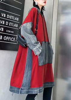 a woman standing in front of a sign wearing a red coat and black leggings