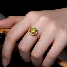 a close up of a person's hand wearing a ring with an orange stone