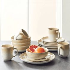 a table topped with plates and cups filled with fruit