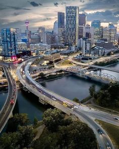 an aerial view of a city at night with cars driving on the road and bridge in the foreground