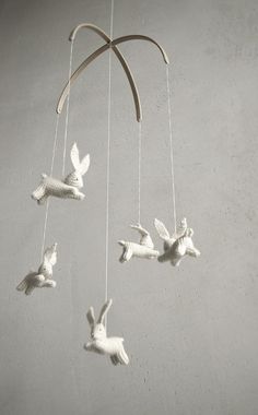 a white crocheted mobile with birds hanging from it's sides and strings