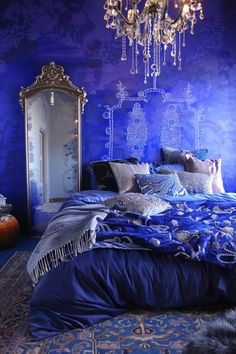 a bedroom with blue walls and a chandelier hanging from the ceiling