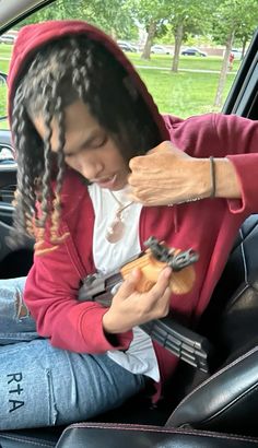 a woman sitting in the back seat of a car holding a cell phone and eating