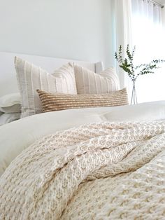 a white bed topped with pillows and blankets