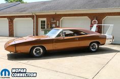 a brown muscle car parked in front of a garage