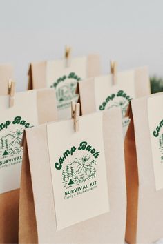 small brown paper bags with green camp bar stickers hanging from clothes pins on them