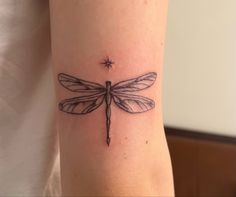 a small dragonfly tattoo on the arm