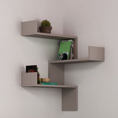 two shelves with books, magazines and plants on them against a white wall next to a bed