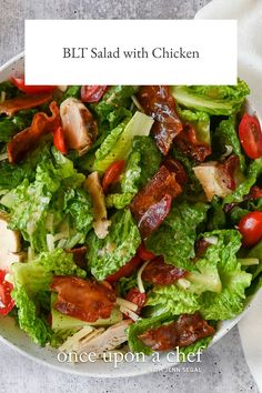 a salad with bacon and lettuce in a white bowl on top of a table