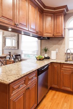 a large kitchen with wooden cabinets and granite counter tops, along with hardwood flooring