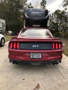 the rear end of a red mustang with its trunk open