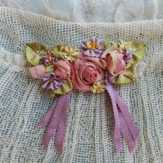 a close up of a piece of cloth with flowers on the side and ribbons attached to it