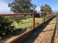 the fence is made of metal wire and has wood posts on each side, along with grass