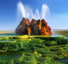 an artistic view of some very colorful rocks in the water and plants growing out of them