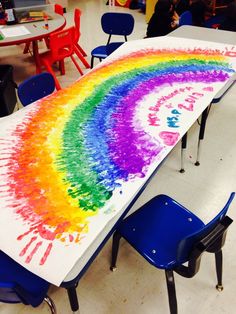 a table with a rainbow painted on it in the middle of a room filled with children's chairs